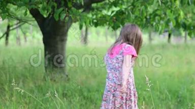 一个可爱的女孩在自然花园里跳舞。 小女孩在一个小蹦床上跳舞和跳跃。 小女孩穿花衣服